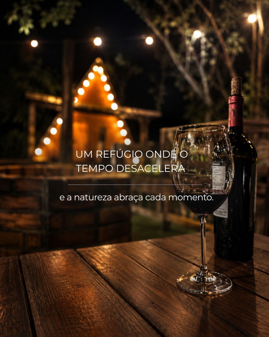 Taça de vinho com a cabana iluminada ao fundo