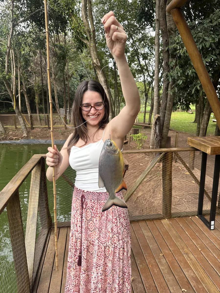 Hóspede exibindo peixe pescado no deck do pesqueiro