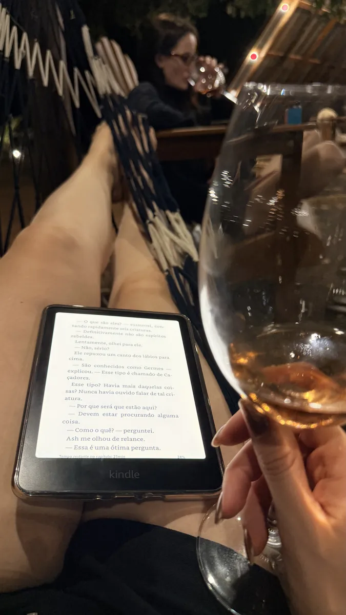 Hóspede lendo na rede com uma taça de vinho à noite